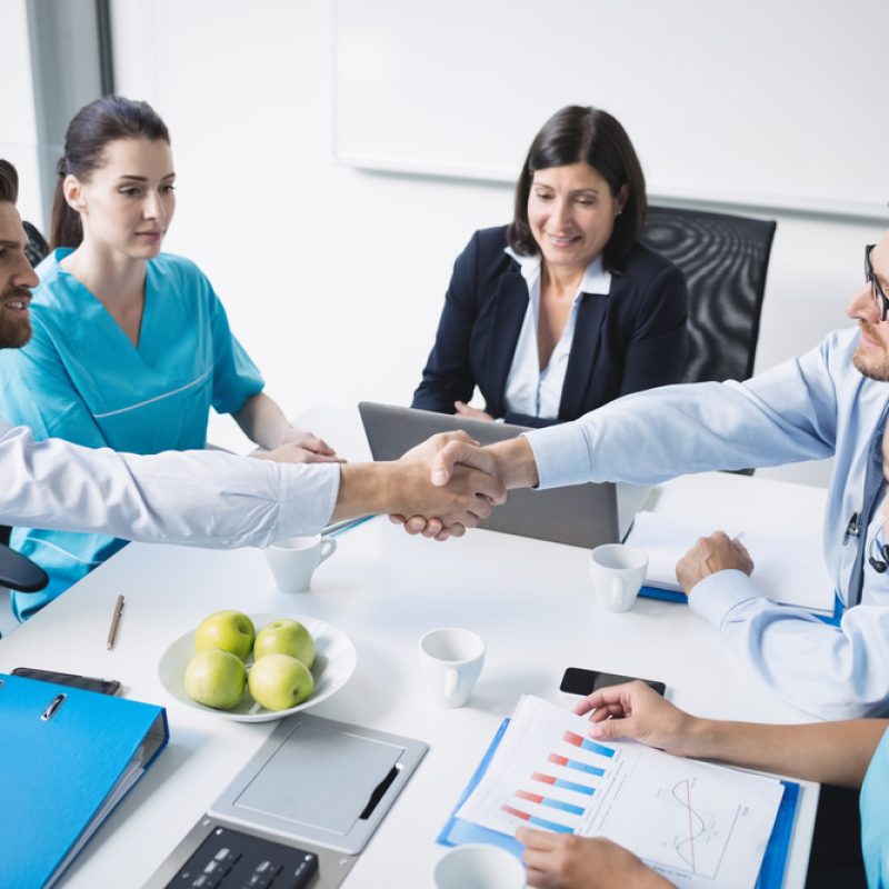Doctors shaking hands with each other in meeting at conference room Doctors shaking hands with each other in meeting at conference room